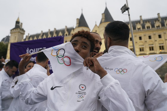 A member of the Refugee Olympic team kisses an Olympic flag as he travels on a boat down the Seine.  [AP/YONHAP]