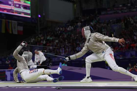 Gu Bon-gil, left, falls during the men's sabre individual round of 32 match against Turkey's Fares Ferjani at the Grand Palais in Paris on Saturday. [YONHAP]