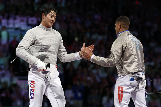 Korea's Oh Sang-uk, left, celebrates after beating Tunisia's Fares Ferjani in the men's sabre individual gold medal bout during the Paris 2024 Olympics at the Grand Palais in Paris on Saturday.  [AFP/YONHAP]