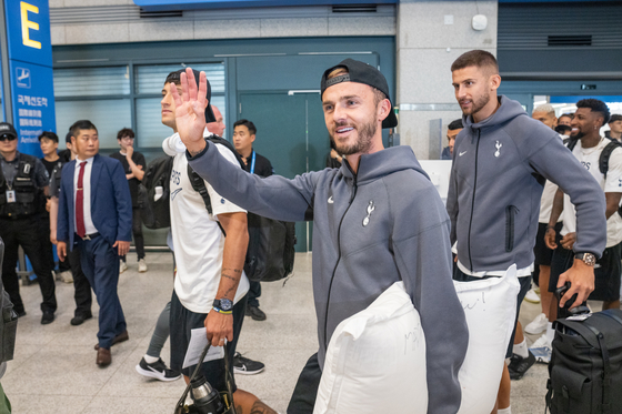 James Maddison, center, waves his right hand as he leaves the airport, holding a pillow with his left arm. [COUPANG PLAY]