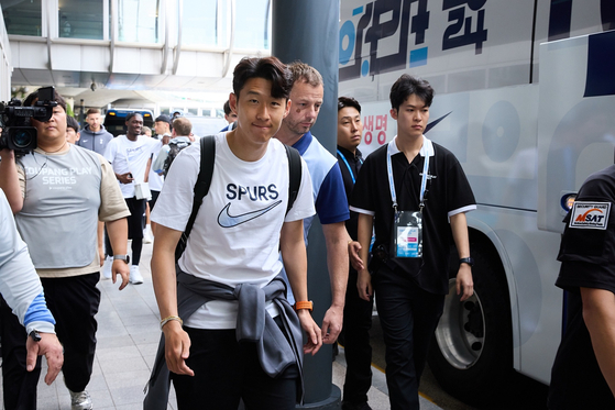 Spurs captain Son Heung-min, center, smiles at the camera before boarding the team bus outside the airport. [COUPANG PLAY]