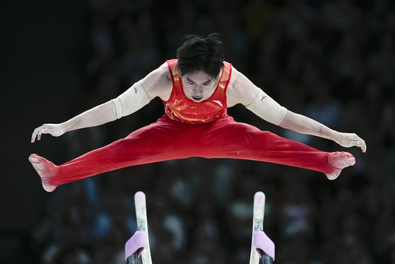 Boheng Zhang of China competes on the parallel bars during a men's artistic gymnastics qualification round at the Paris Olympics in Paris on Saturday. [AP/YONHAP]