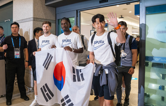Tottenham Hotspur's Ben Davies, left, Yves Bissouma and Son Heung-min hold the Korean flag as they walk through the arrivals gate at Incheon International Airport in Incheon on Sunday. [COUPANG PLAY]