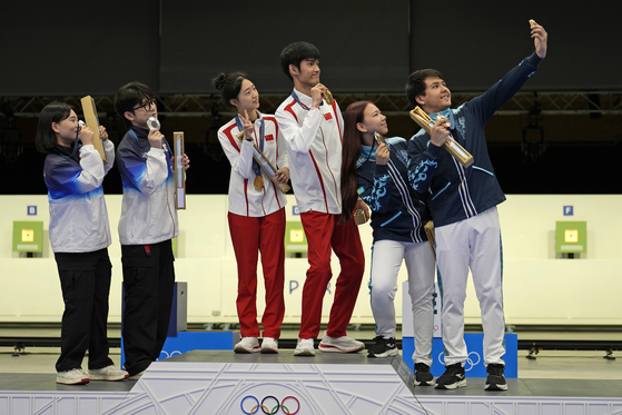 Islam Satpayev, right, of Kazakhstan uses his phone to take a selfie with fellow medal winners teammate Alexandra Le, second right, and right to left, gold medalists China's Sheng Lihao and Huang Yuting, and silver medalists Korea's Park Ha-jun and Keum Ji-hyeon after the medal ceremony for the 10m air rifle mixed team competition at the 2024 Paris Olympics in Chateauroux, France on Saturday.  [AP/YONHAP]