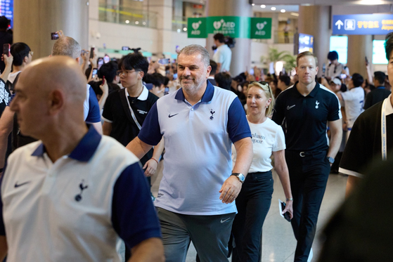 Tottenham Hotspur manager Ange Postecoglou, center, smiles as he walks through the terminal. [COUPANG PLAY]