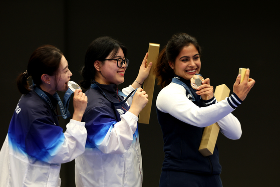 From left, women's 10-meter air pistol silver medalist, Korea's Kim Ye-ji, gold medalist, Korea's Oh Ye-jin, and bronze medalist, India's Manu Bhaker, take a selfie on the podium during the Paris 2024 Olympics on Sunday. [SAMSUNG ELECTRONICS/GETTY IMAGES]