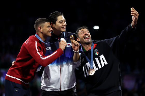 Korea's Oh Sang-uk, centre, winner of the gold medal in the men's individual Sabre competition, takes selfies with the event's silver medalist, Tunisia's Fares Ferjani, left, and bronze medalist, Italy's Luigi Samele, during the Paris 2024 Olympics, using the Samsung Galaxy Z Flip 6. [SAMSUNG ELECTRONICS/GETTY IMAGES]