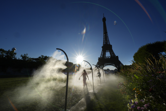 A spectator walks through water mist sprayers on her way to the Eiffel Tower Stadium to watch a beach volleyball game in Paris on Sunday.  [AP/YONHAP]