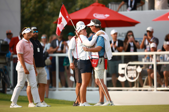 Lauren Coughlin of the United States, center, reacts on the 18th green after the final round of the CPKC Women's Open at Earl Grey Golf Club on Sunday in Calgary, Alberta, with Korea's Ryu Hae-ran to the side. [AFP/YONHAP]