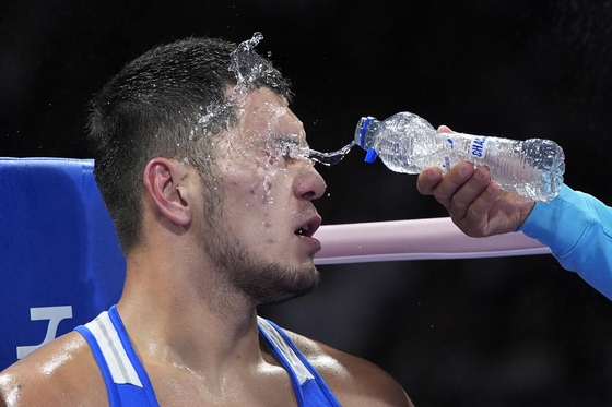 Kazakhstan's Aibek Oralbay is sprayed by water between rounds against Nigeria's Olaitan Olaore during the men's 92kg boxing preliminary in Paris on Sunday.  [AP/YONHAP]