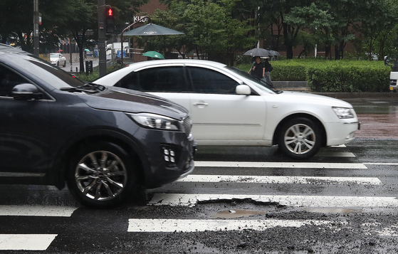 A black car is about to drive over a pothole in Seoul on July 18. [NEWS1] 