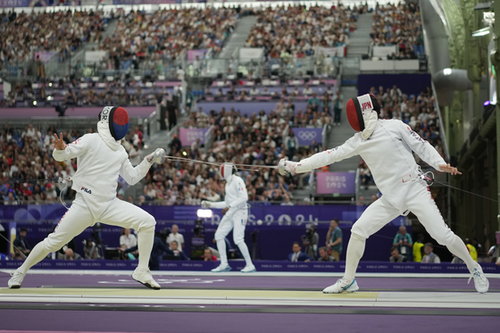 Korea's Kim Jae-won, left, and Japan's Kano Koki compete in the men's individual Epee table of 32 during the Paris Olympics at Grand Palais in Paris on Sunday. [AP/YONHAP]