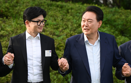 President Yoon Suk Yeol, right, locks hands with new People Power Party (PPP) Chairman Han Dong-hoon for a commemorative photo ahead of a dinner for the PPP's new leadership in front of the Yongsan presidential office in central Seoul on Wednesday evening. [PRESIDENTIAL OFFICE]