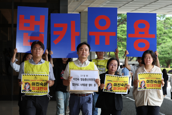 Member of civic groups comprised of media workers hold up placards protesting Lee Jin-sook's appointment as chair of the Korea Communications Commission as they walk into the Seoul Central District Prosecutors' Office on Wednesday to submit a complaint against her for allegedly misusing corporate cards issued by MBC. [YONHAP]