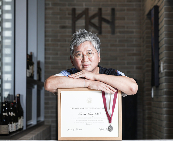 Architect Hong Tae-sun poses with his Fellow of the American Institute of Architects certification at the YKH Associates Headquarters in Gangnam District, southern Seoul, on June 17. [JOONGANG ILBO]