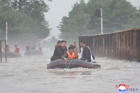 North Korean leader Kim Jong-un, left, rides in a lifeboat to inspect flood-hit areas in North Korea's border city of Sinuiju in this photo carried by Pyongyang's state-controlled Korean Central News Agency on Wednesday. [YONHAP]