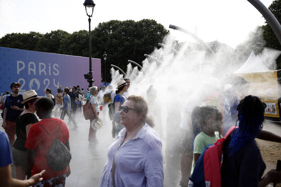 Spectators cool off in the hot weather before the start of the archery at the Paris Olympics in Paris on Wednesday. [REUTERS/YONHAP]