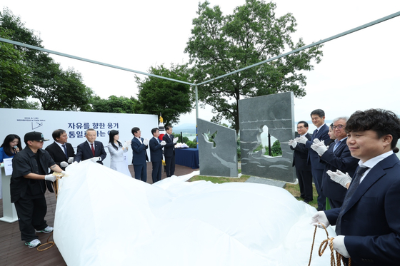 A monument erected to commemorate North Korean defectors who lost their lives trying to escape the regime in Paju, Gyeonggi, is unveiled in a ceremony for together in a ceremony attended by Unification Minister Kim Yung-ho, Tae Yong-ho, secretary-general for the Peaceful Unification Advisory Council, and some 60 defectors. [YONHAP]