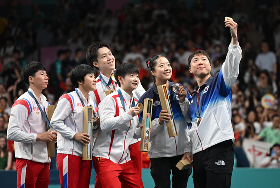 Table tennis player Lim Jong-hoon, far right, takes a selfie with his teammate Shin Yu-bin, right, Team China and Team North Korea. [HERALD BIZ]