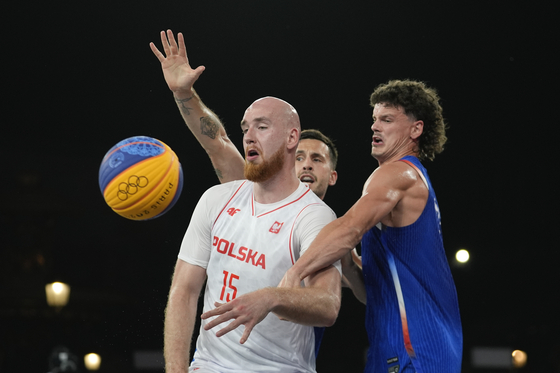 Adrian Bogucki of Poland passes, defended by France's Jules Rambaut, back, and Franck Seguela, right, in a men's 3x3 basketball match between Poland and France in Paris on Wednesday.  [AP/YONHAP]