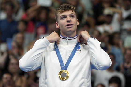 Gold medalist Leon Marchand stands on the winner's podium following the men's 200-meter breaststroke final at the 2024 Paris Olympics on Wednesday in Nanterre, France. [AP/YONHAP]