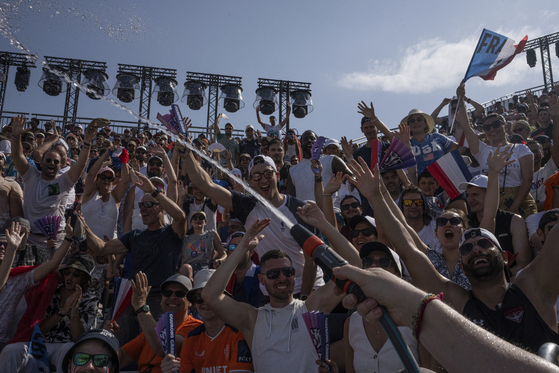 A staff member sprays water on spectators during a women's beach volleyball match at Eiffel Tower Stadium in Paris on Wednesday.  [AP/YONHAP]