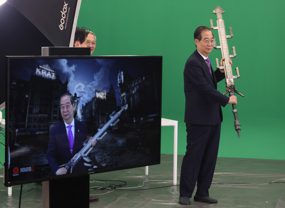 Prime Minister Han Duck-soo holds a sword from the game Lies of P during his visit to the headquarters of Neowiz, the global publisher of Lies of P, in Pangyo, Gyeonggi. [YONHAP]