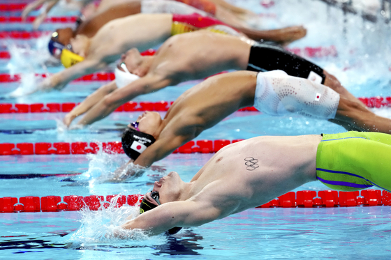 Swimmers plunge for a men's 4x100-meter medley relay heat in Paris on Saturday.  [AP/YONHAP]