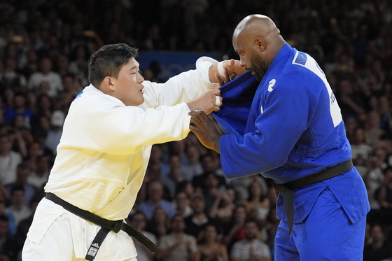Korea's Kim Min-jong, left, and France's Teddy Riner compete in the men's 100-kilogram gold medal match at the Champ-de-Mars Arena in Paris on Friday.  [AP/YONHAP]