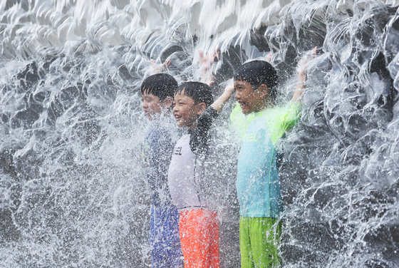 Children stand in a fountain at a park in Suwon, Gyeonggi, on Sunday as they beat the extreme heat wave that continued to strike the country. The midday high in Yeoju, Gyeonggi, rose to 40 degrees Celsius on the same day, the first time in six years that temperatures reached 40 degrees in the country. [YONHAP] 