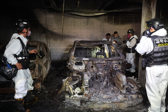 Firefighters inspect an underground parking lot in Incheon where a Mercedes EV caused a fire after exploding last week. A total of 140 cars were damaged, 40 of which were completely burned. [YONHAP] 