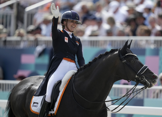 Netherlands' Emmelie Scholtens waves while riding Indian Rock during the dressage individual grand prix freestyle in Versailles on Sunday.  [AP/YONHAP]