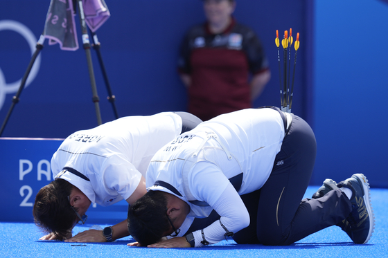 Korea's Kim Woo-jin, right, and coach Park Seong-su bow deeply to fans after Kim won gold in the men's individual archery final in Paris on Sunday.  [AP/YONHAP]
