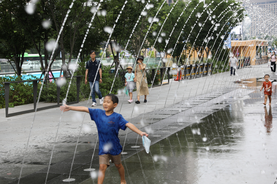 A child runs around in a fountain in Gwanghwamun Plaza in Jongno District, central Seoul, on Monday to beat the extreme heat wave that continued to bake the country. [NEWS1]