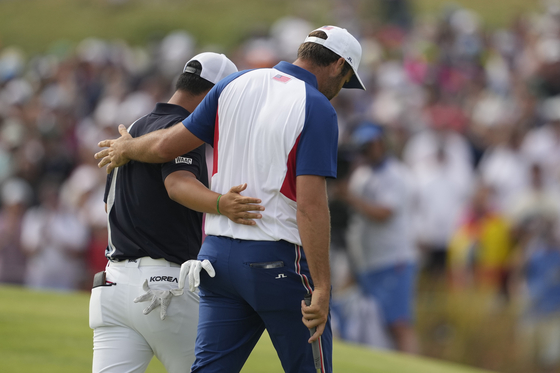 Scottie Scheffler of the United States, right, and Tom Kim of Korea walks arm in arm from the 18th green after completing the final round of the men's golf tournament at Le Golf National in Saint-Quentin-en-Yvelines, France on Sunday. [AP/YONHAP]