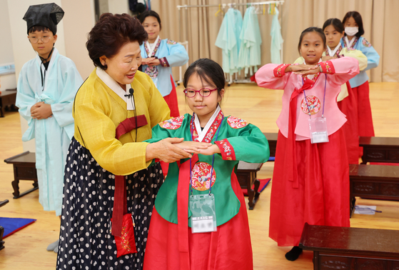 Students participate in a traditional etiquette education session during a summer school extracurricular program at the Chungnyeolsa Shrine in Busan on Monday. [YONHAP]