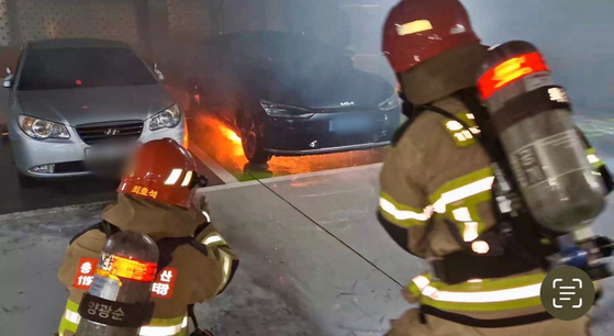 Firefighters work to extinguish a blaze that broke out from an EV car in a parking lot in South Chungcheong. [NEWS1]