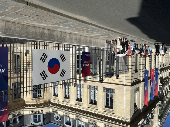 Visitors line up outside Korea House 30 minutes before the doors open in Paris on Monday.  [JIM BULLEY]