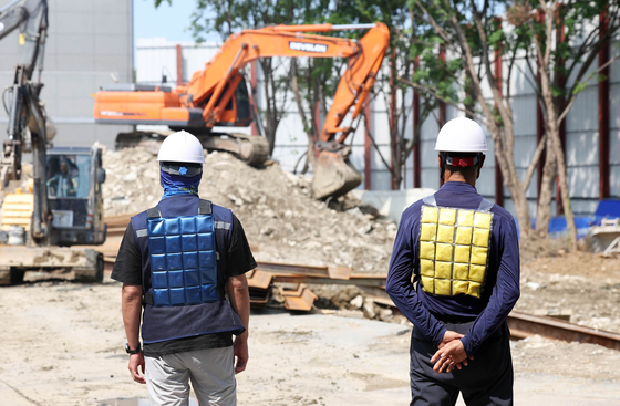 Construction workers wear cooling vests to cool down at a construction site in Buk District, Gwangju, on Tuesday. [GWANGJU BUK DISTRICT OFFICE]