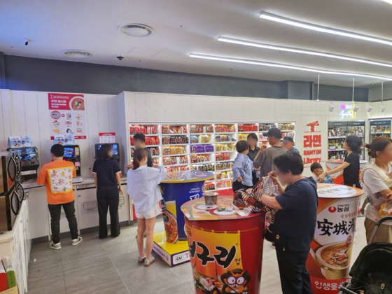 Customers browse instant noodle products items at CU's ″ramyeon library″ on Jeju Island. [CU]