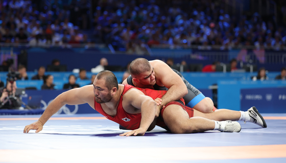 Korean wrestler Lee Seung-chan, left, competes in the men’s Greco-Roman 130-kilogram repechage match against Amin Mirzazadeh of Iran at the Paris Olympics at Champ-de-Mars Arena in Paris on Tuesday. [YONHAP]