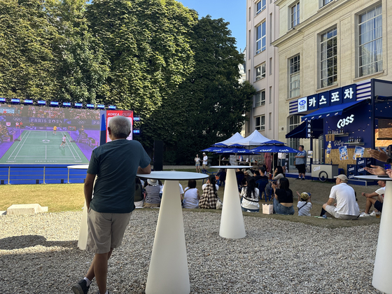 Spectators gather in the shade at Korea House to watch An Se-young compete in the women's badminton final in Paris on Monday.  [JIM BULLEY]