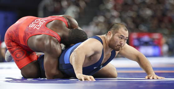 Korean wrestler Lee Seung-chan, right, competes in the men’s Greco-Roman 130-kilogram round of 16 against Mijain Lopez of Cuba at the Paris Olympics at Champ-de-Mars Arena in Paris on Monday. [YONHAP]