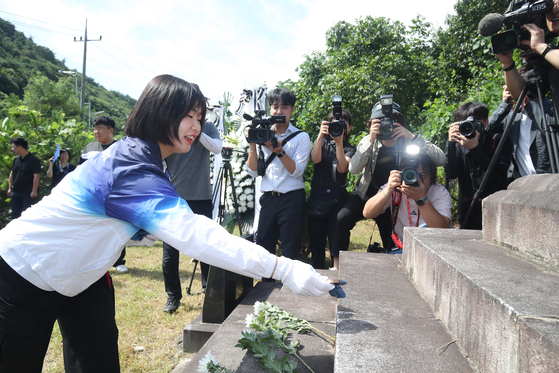 Judoka Huh Mi-mi places her Olympic medals on a memorial stone for her great-grandfather, who was an independence activist during the 1910-1945 Japanese colonial rule, in Gunwi County in Daegu on Tuesday. [NEWS1]