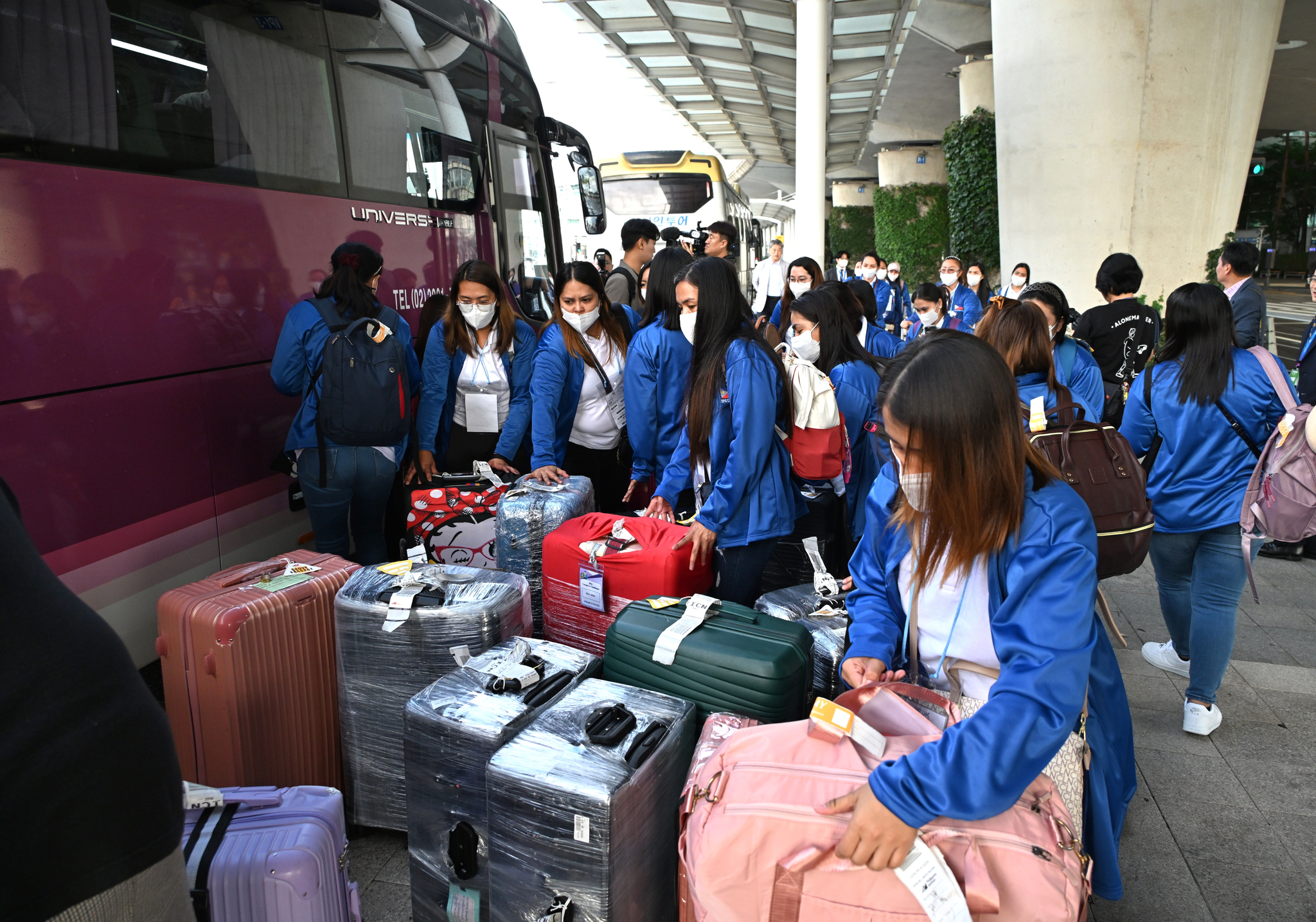 Filipino caregivers sort their luggage before boarding a bus provided by the Seoul city government at Incheon International Airport on Tuesday. [SEOUL METROPOLITAN GOVERNMENT]
