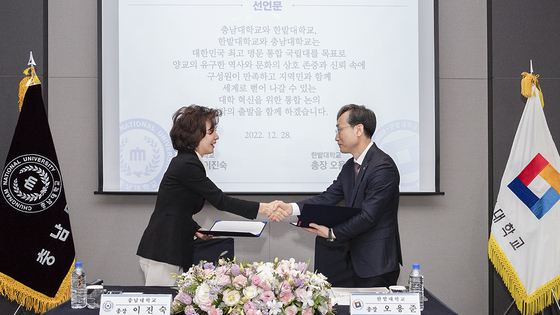 Presidents of Chungnam National University and Hanbat National University shake hands during a meeting to discuss the two universities' merger in 2022. [CHUNGNAM NATIONAL UNIVERSITY]