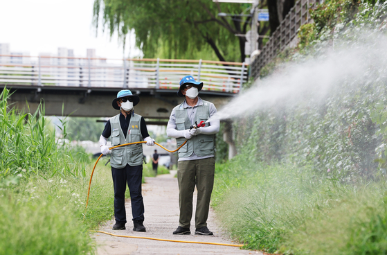 Health officials spray insecticide to kill mosquitoes capable of carrying malaria and Japanese encephalitis near Suwon Stream in Suwon, Gyeonggi, on July 31. [YONHAP] 