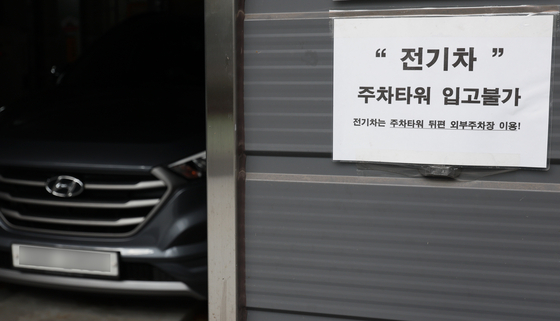 A notice stuck on a parking tower surface in Mapo District, southern Seoul, on Wednesday reads "Electric vehicles are not allowed to enter the parking tower. Electric vehicles should use the outdoor parking lot behind." [YONHAP]