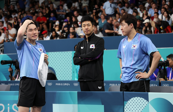 Korean table tennis players Jang Woo-jin, left, Lim Jong-hoon react during the men's team quarterfinals at the Paris Olympics against China at the Paris Arena in Paris on Wednesday. [YONHAP] 