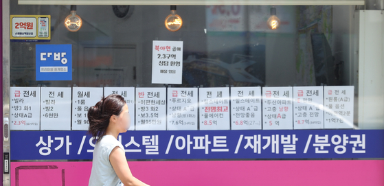 A woman passes by a real estate agency situated in downtown Seoul on Wednesday. [YONHAP]